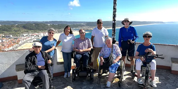 Group of wheelchairs at scenic point overlooking city and beach.