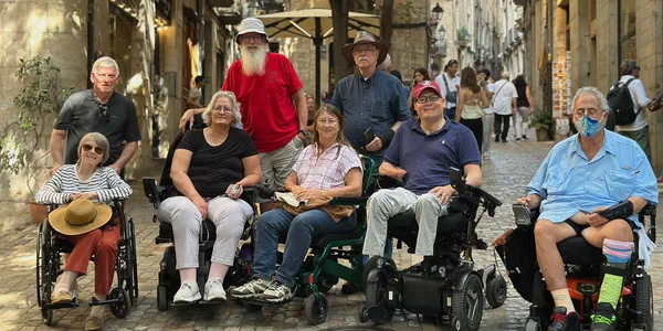 Group of wheelchair users posing for a picture on a Spanish street.