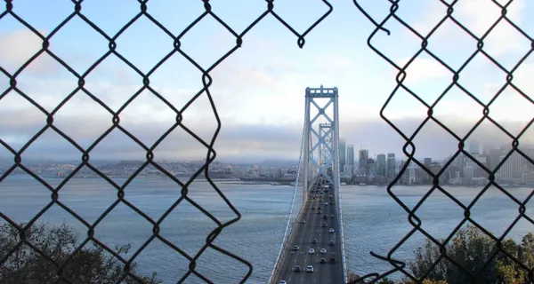 Bridge seen through wire fence.