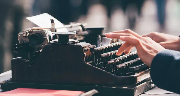 Hands typing on a typewriter.