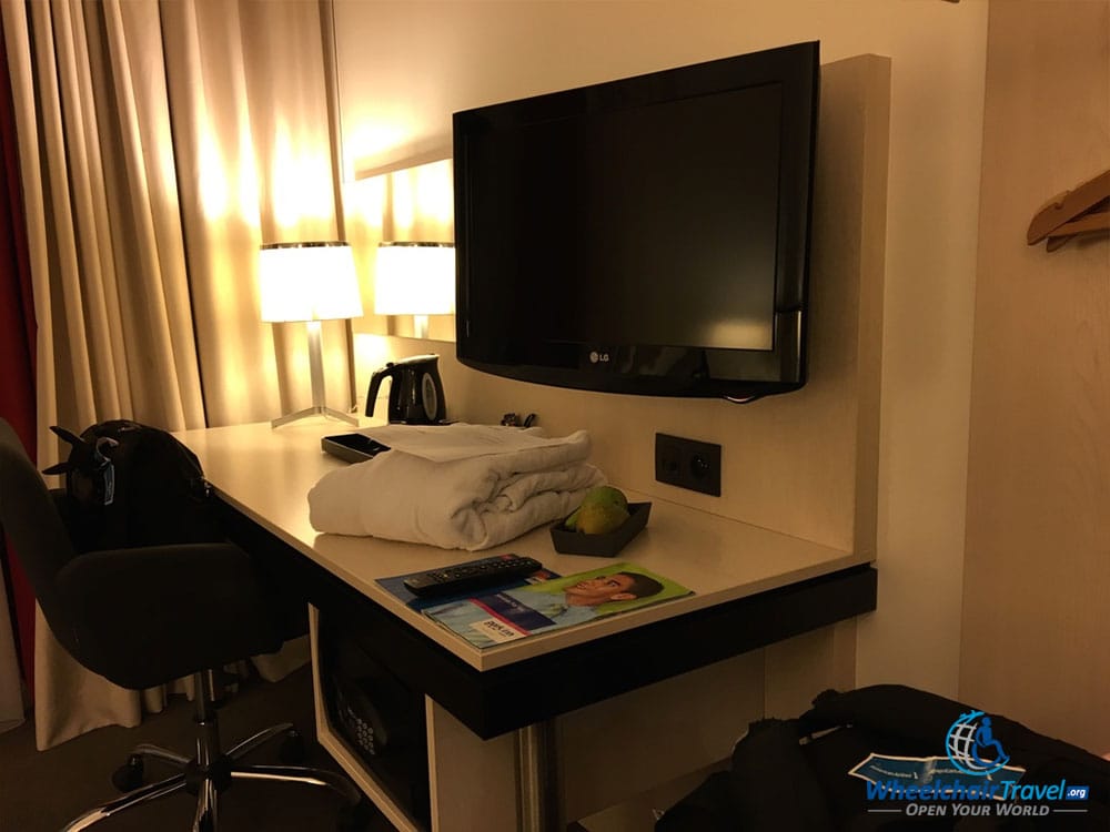 Photo Description: Desk and flat screen television set opposite the beds, along the wall.