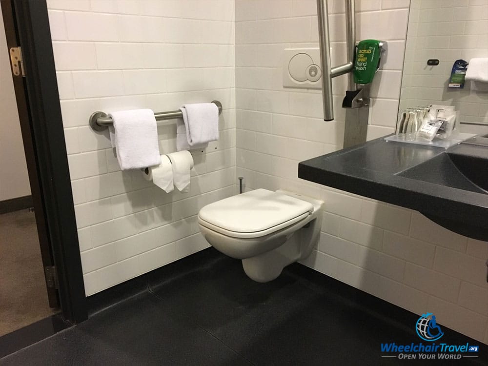 Photo Description: Toilet in hotel bathroom with grab bar along wall.