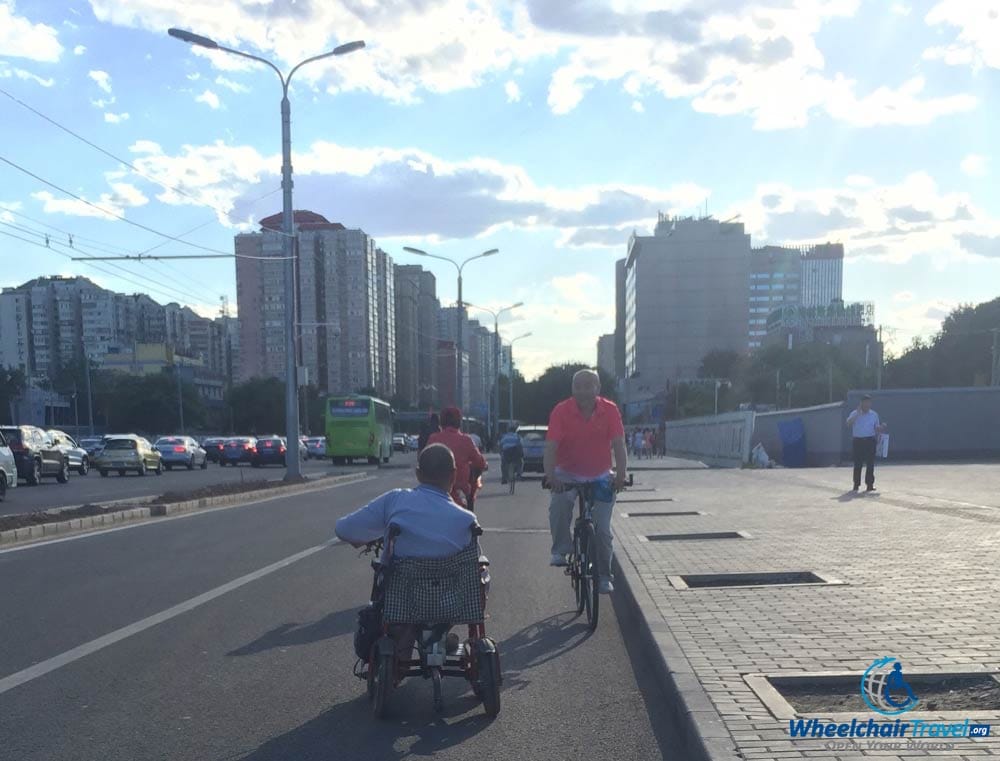 PHOTO DESCRIPTION: A local wheelchair user in a Beijing street because there was no curb cut on the sidewalk.