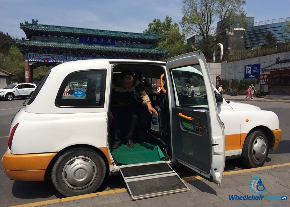 London Cab-style wheelchair taxi parked at the Badaling Great Wall site, with its wheelchair ramp extended.