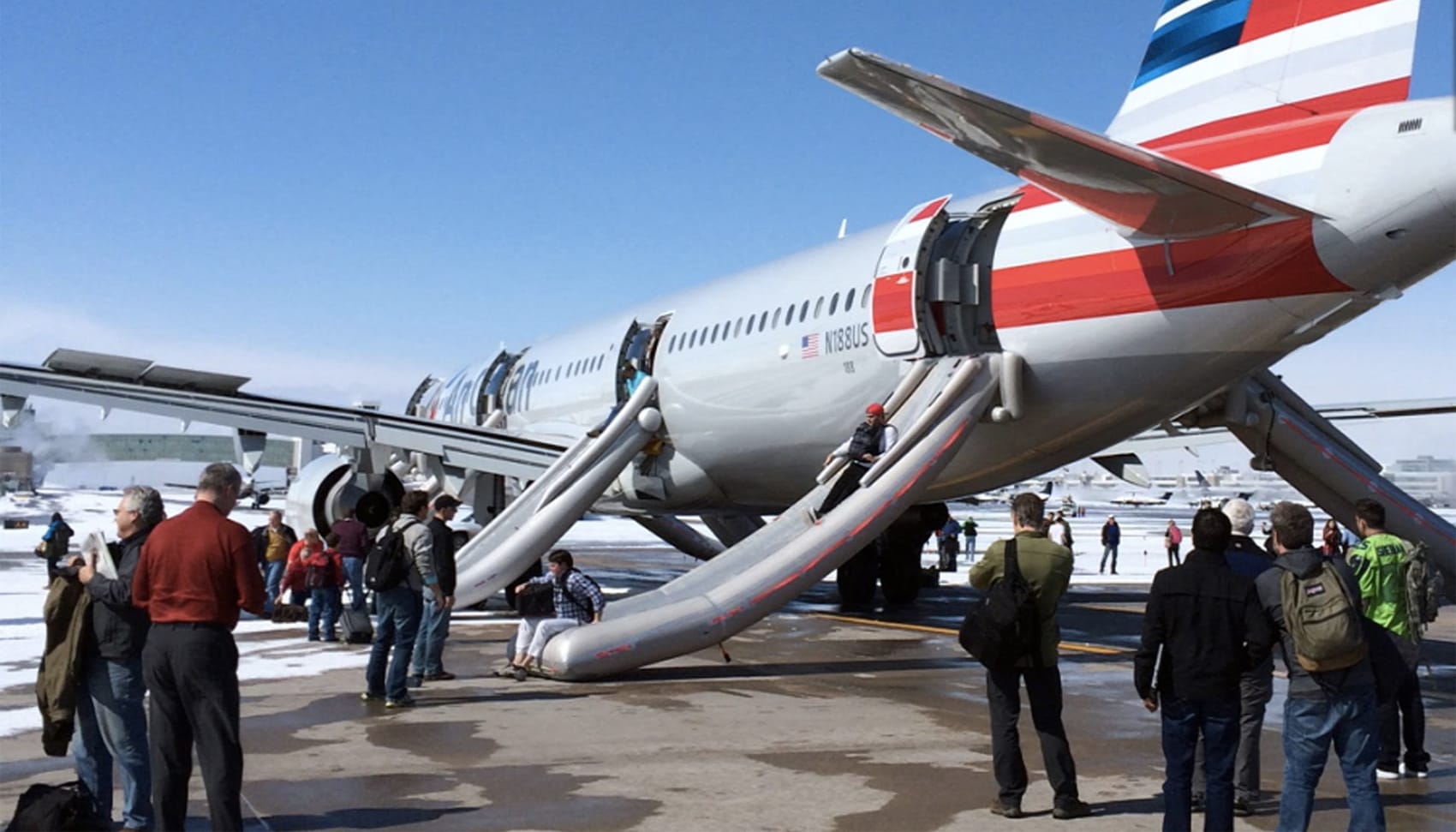 Photo Description: An American Airlines aircraft on a runway at Denver International Airport, with its emergency evacuation slides deployed