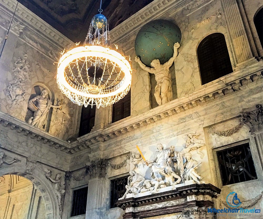 PHOTO DESCRIPTION: A marble sculpture of Atlas with the earth on his shoulders, set high on a wall near to the ceiling in the great hall.