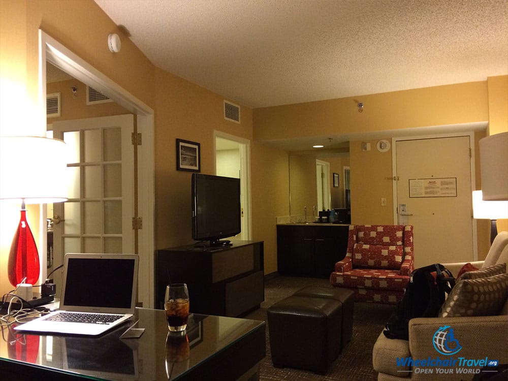 PHOTO DESCRIPTION: The room's living area seen from the opposite direction and behind the desk, with a doorway to the bathroom and a wetter at the far end.