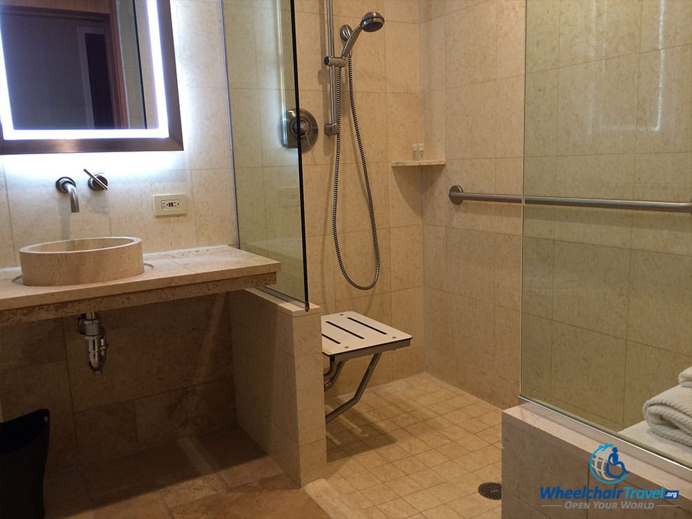 PHOTO DESCRIPTION: Roll-in shower with shower bench and handheld shower nozzle.