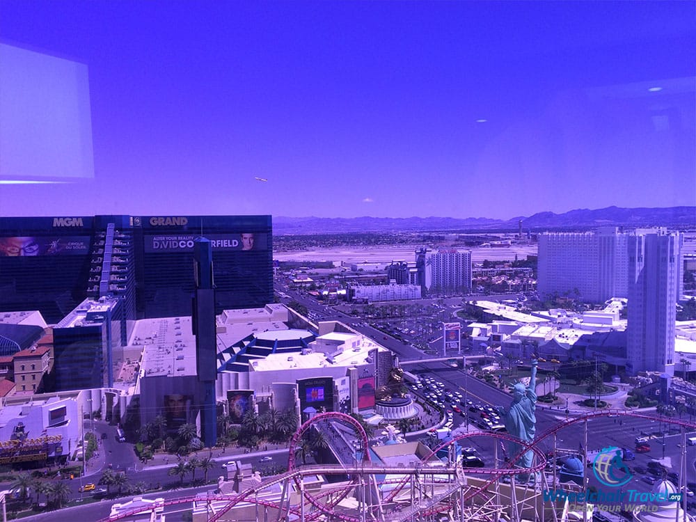 PHOTO DESCRIPTION: View from the room's window, with the Las Vegas Strip and New York-New York roller coaster down below, and the Las Vegas Airport in the background.