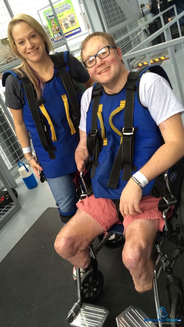 PHOTO DESCRIPTION: John pictured in the SlotZilla wheelchair wearing a safety and attachment harness.