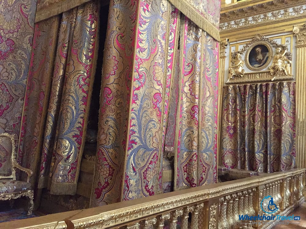 PHOTO DESCRIPTION: A large bed with drapes extending down from the ceiling, circling the bed on all sides.