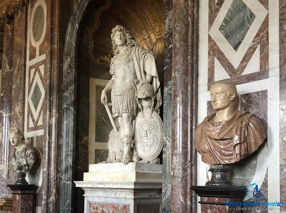 PHOTO DESCRIPTION: A marble wall in a drawing room, with a statue and two busts along the wall.