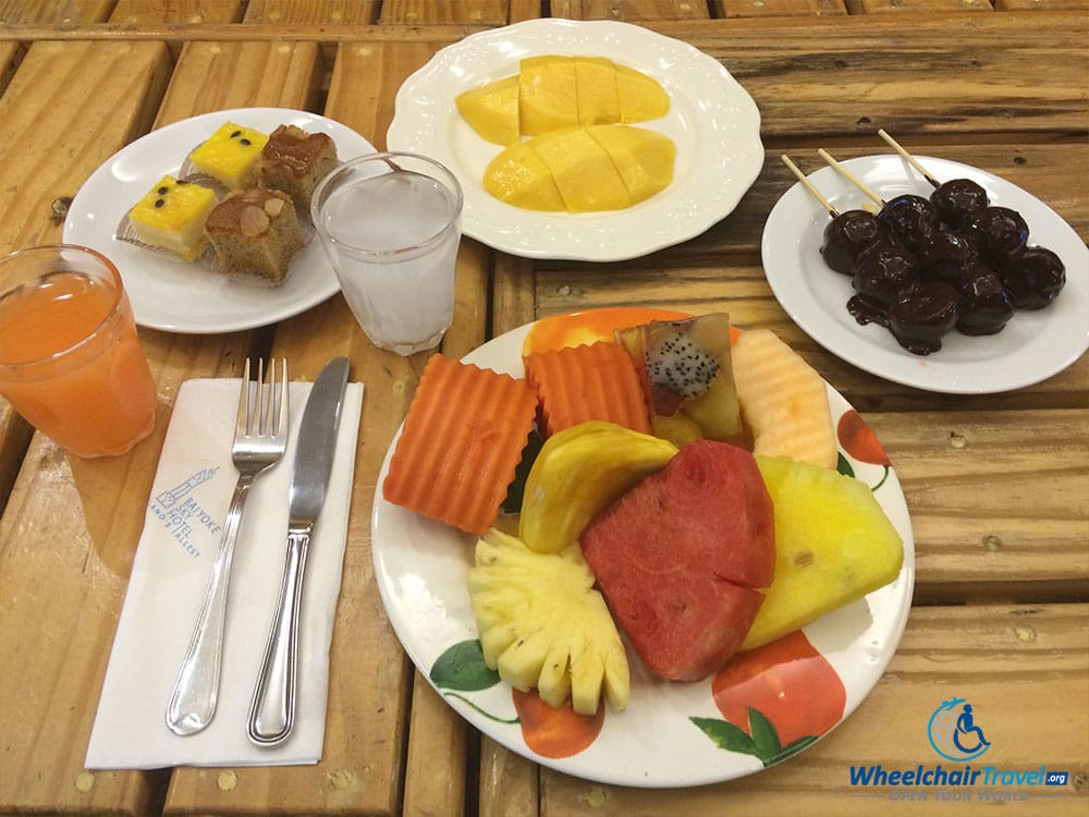 PHOTO DESCRIPTION: Various fruits laid out on 4 different white plates and spread across a table.