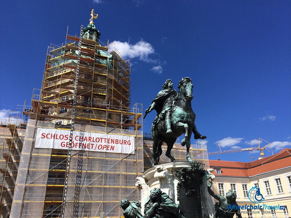 PHOTO DESCRIPTION: Cupola Dome of Charlottenburg Palace covered in scaffolding and under construction, with the statue of Friedrich Wilhelm I seen in foreground.