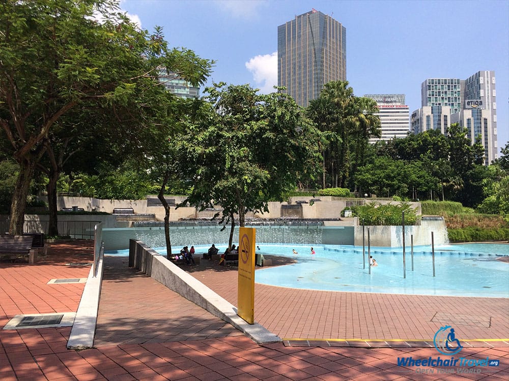 PHOTO DESCRIPTION: Wheelchair ramp leading down to a splash pool in the Kuala Lumpur City Center Park.