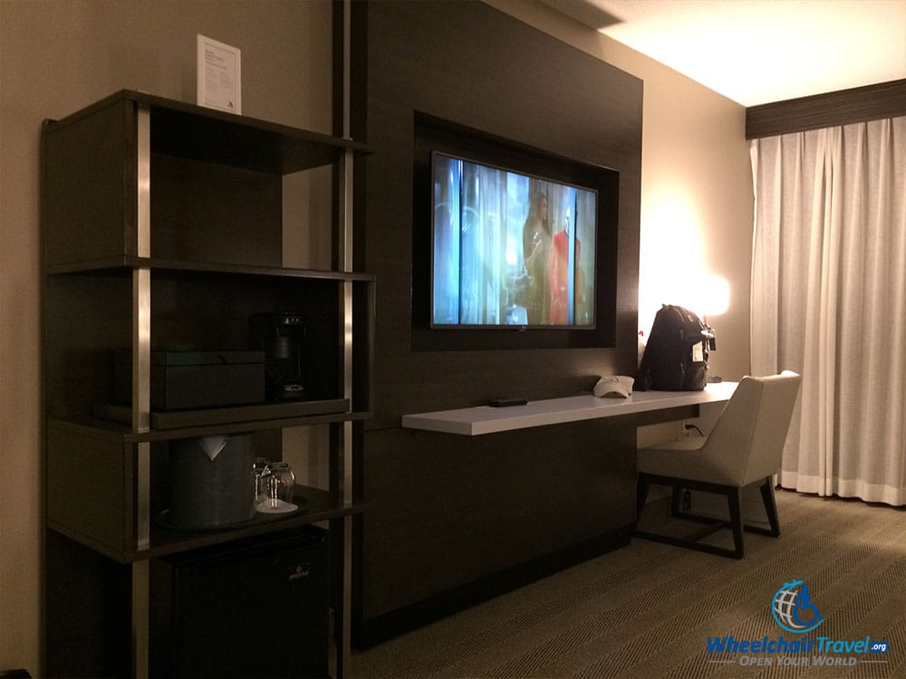 PHOTO DESCRIPTION: TV and desk on wall opposite the bed.