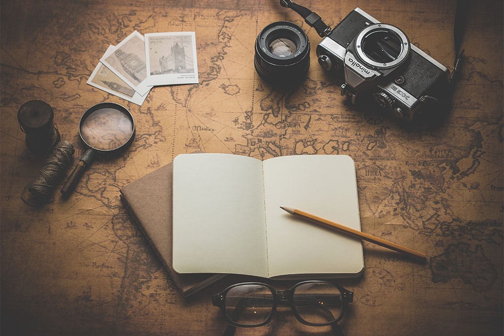 PHOTO: World map with a passport, camera and spectacles laid on top of it.