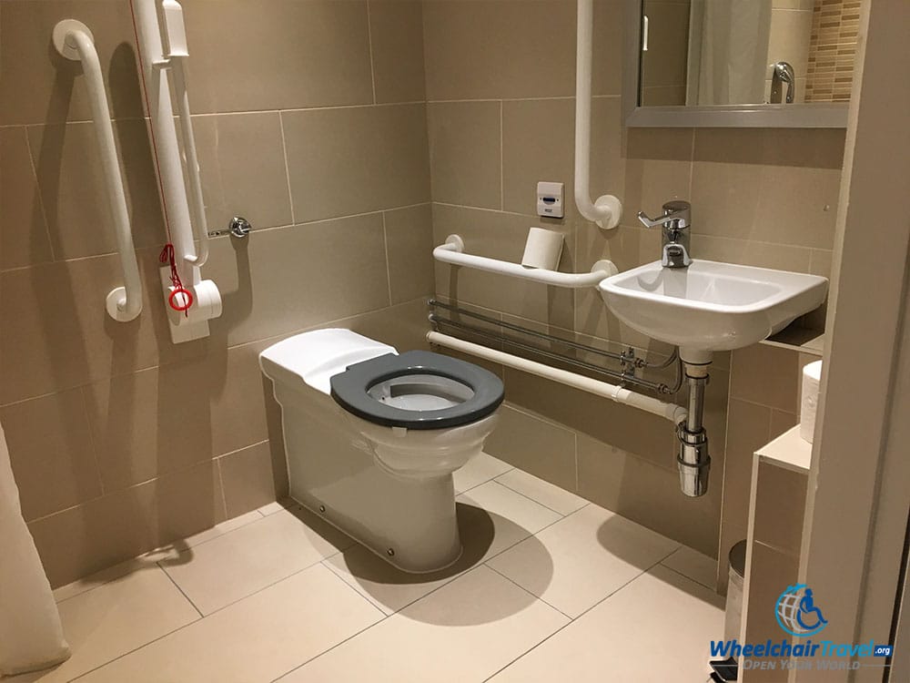 Wheelchair accessible toilet with grab bars and a small sink