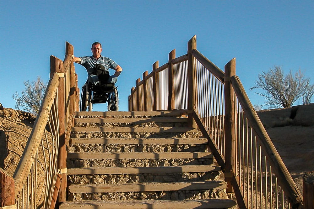 Dave, seated in his wheelchair, at the top of an outdoor set of steps.