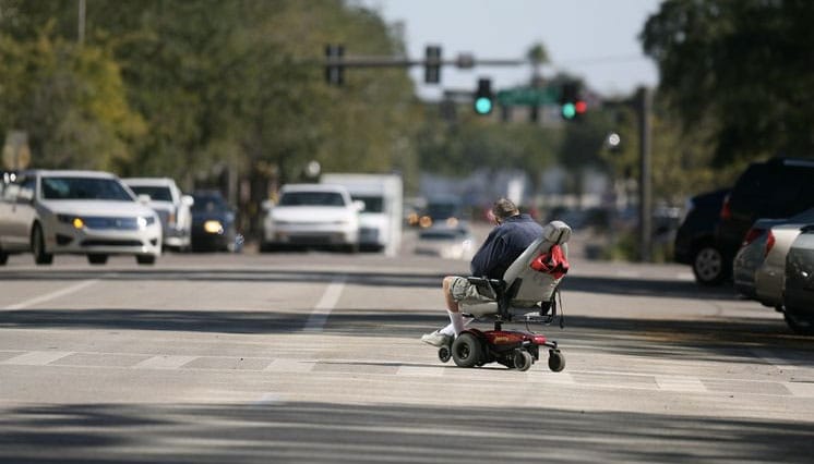 Man crossing the road in a power wheelchair