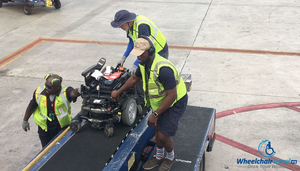 Power wheelchair being loaded into airplane cargo hold using a belt loader