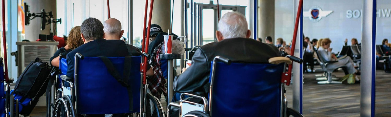 Wheelchair users lined up to board an airplane at the airport gate