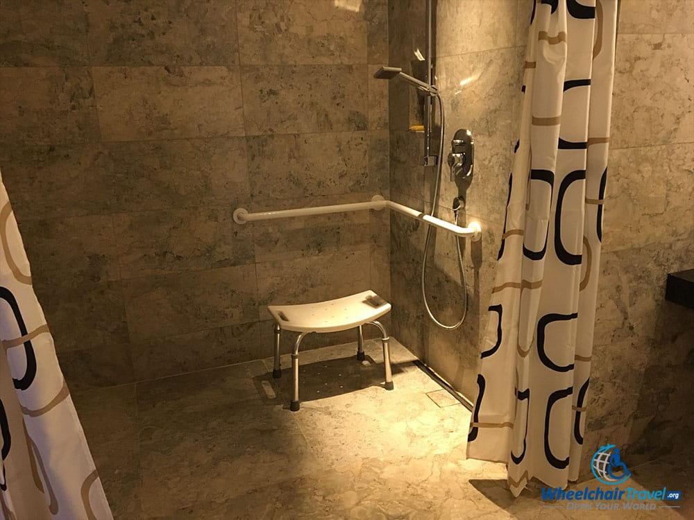 Roll-in shower with grab bars and a portable shower chair.