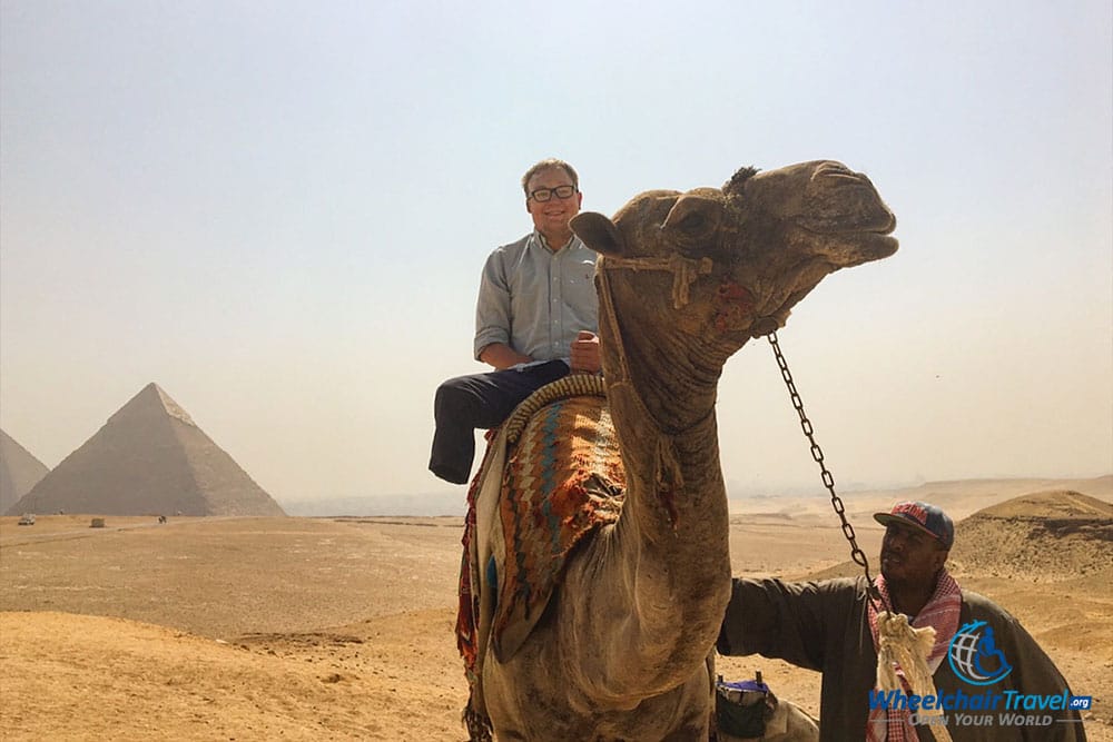 Wheelchair user John Morris riding a camel around the Pyramids of Egypt.