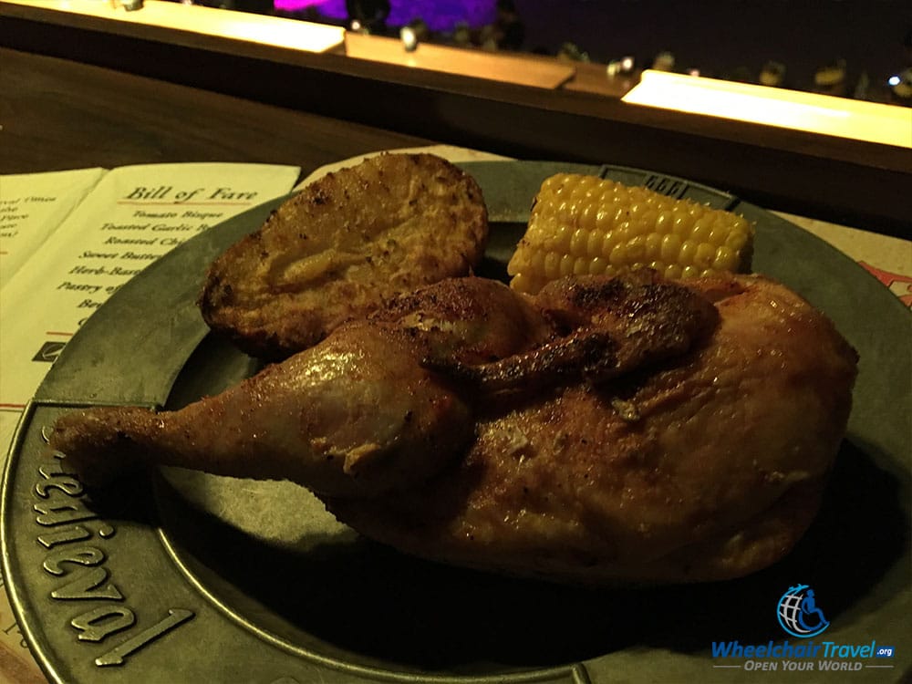 Chicken entree with corn on the cob and a potato.