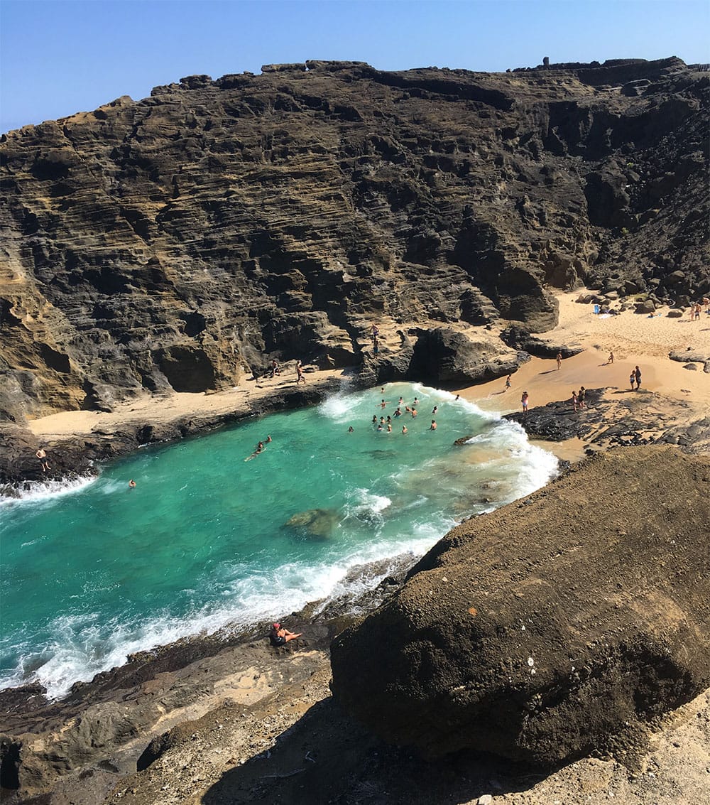 A hawaii beach between two rocky cliffs.