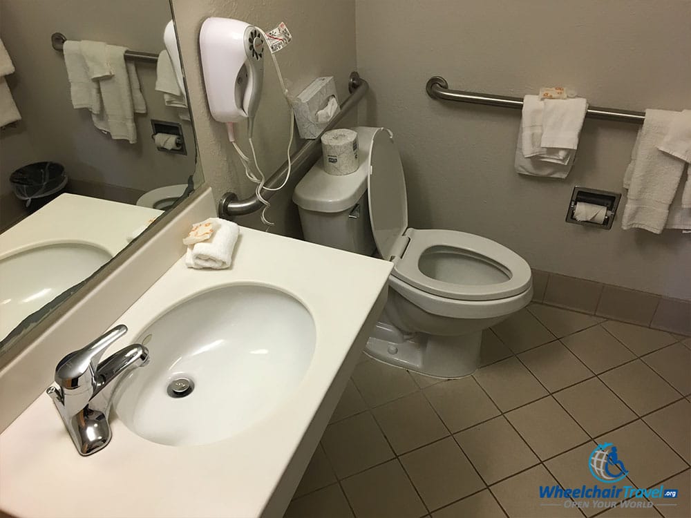 Bathroom sink and toilet with grab bars.