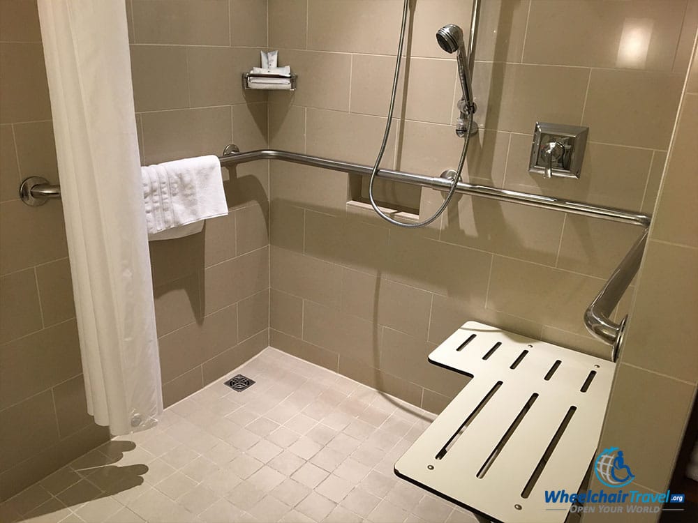 Roll-in shower with built-in shower seat and grab bars.