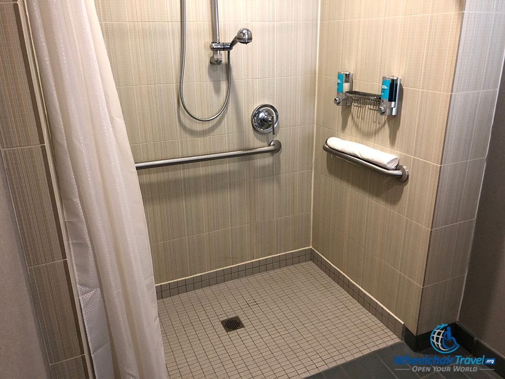 Roll-in shower with wall-mounted soap dispensers at an Aloft hotel.