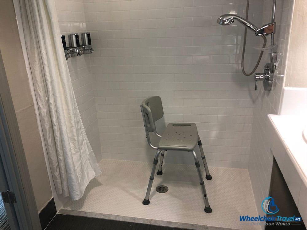 Roll-in shower with wall-mounted soap dispensers at a Four Points by Sheraton hotel.