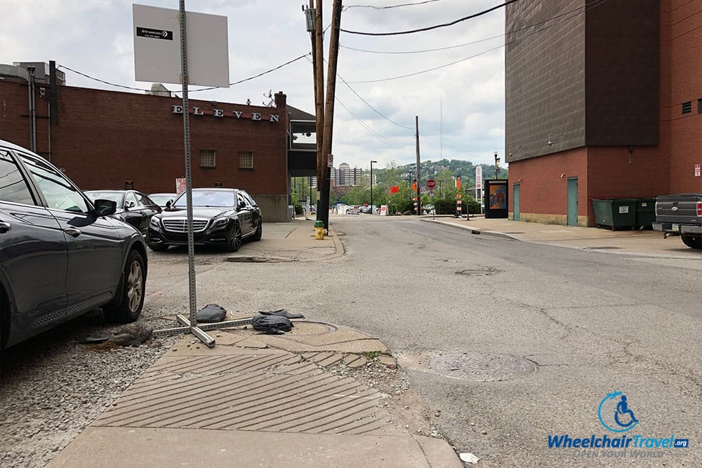 Cracked pavement and misaligned curb ramp.