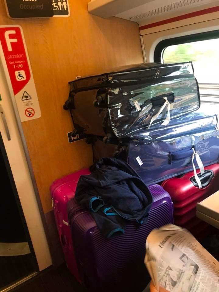 Stack of bags blocks wheelchair space on train.