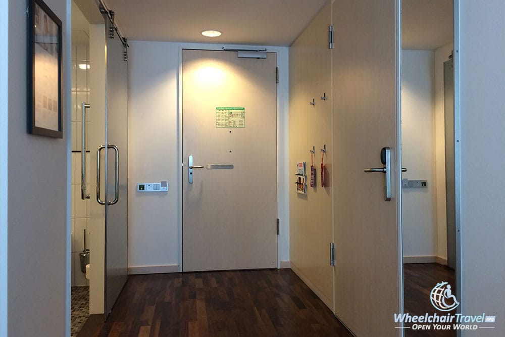 Interior corridor with accessible path to bathroom and full-length mirror.