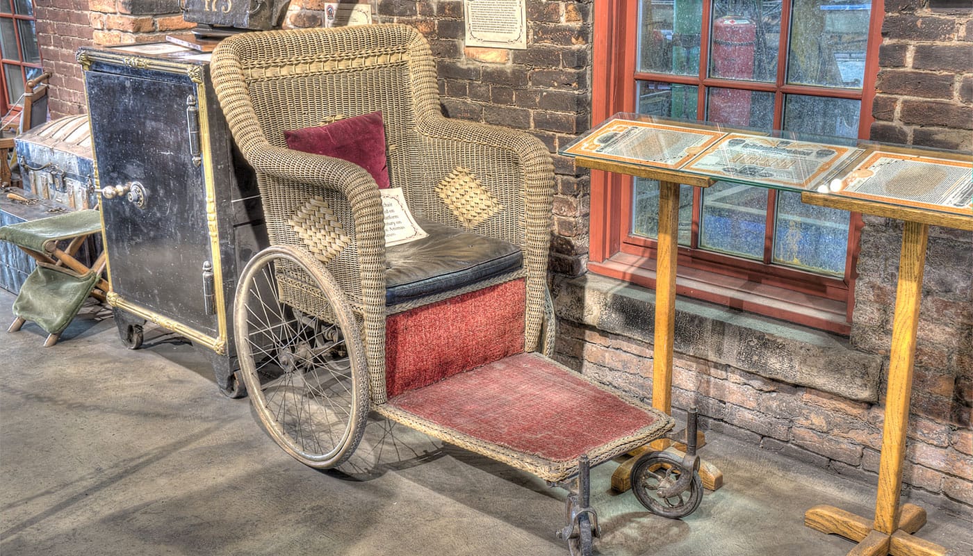 Historic wheelchair displayed in a museum.