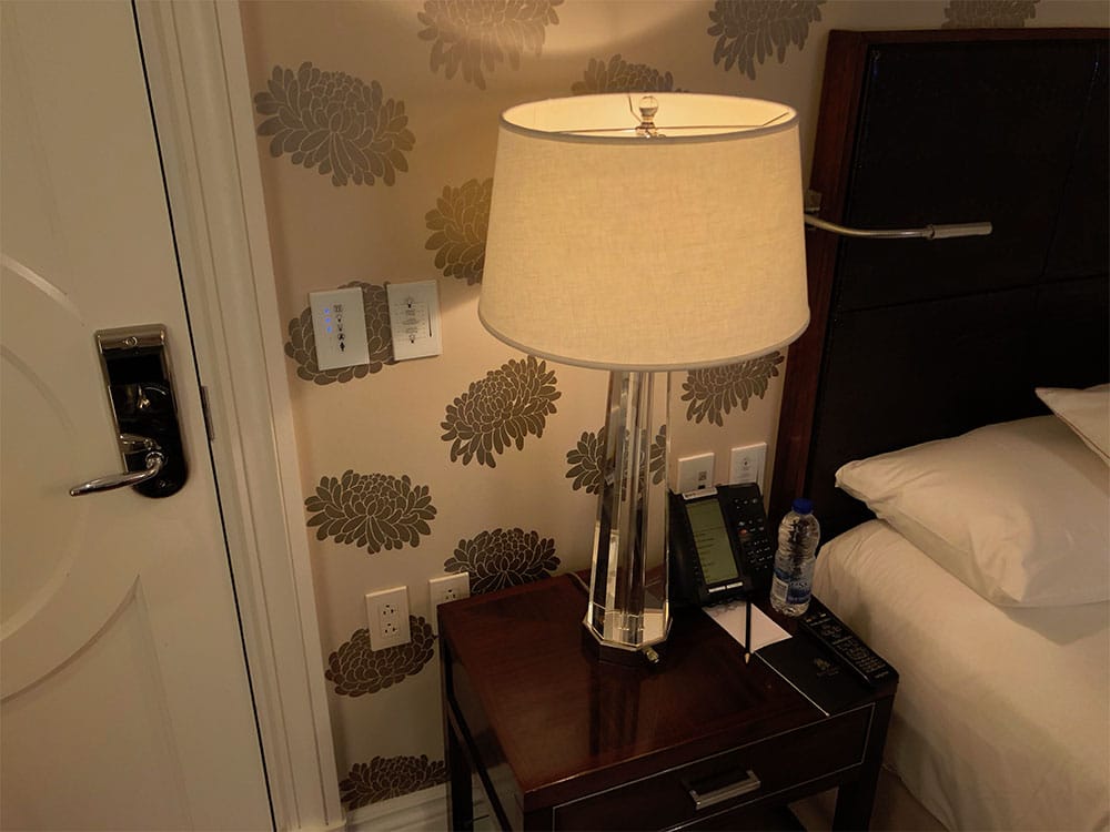 Nightstand with lamp, telephone and access to power.