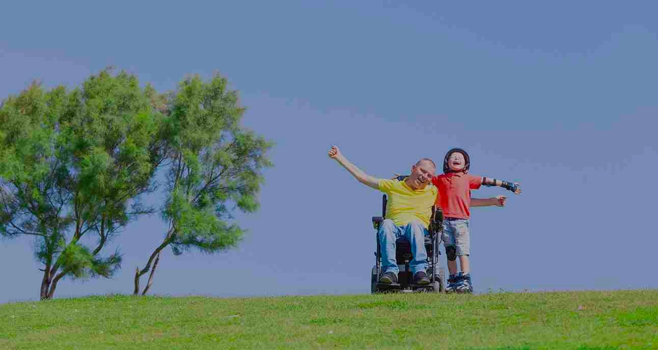 Man with wheelchair and child on the lawn.