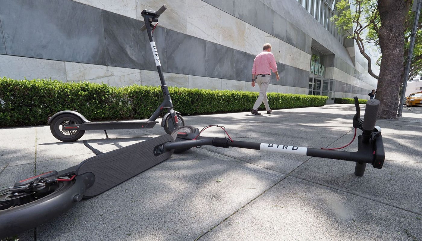 Two bird scooters on a sidewalk in Los Angeles, CA.