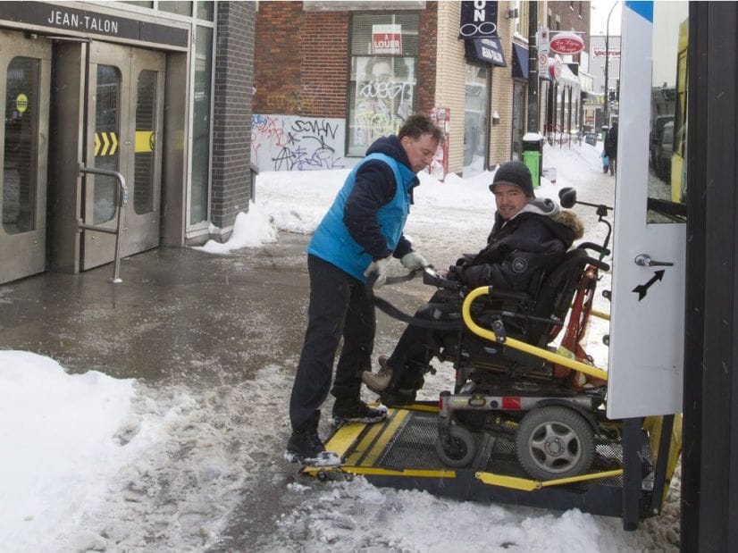 Man with wheelchair on lift of Paratransit bus.