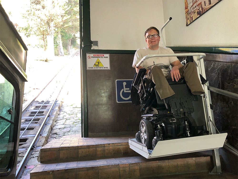 Riding the wheelchair lift to the top of the stairs.