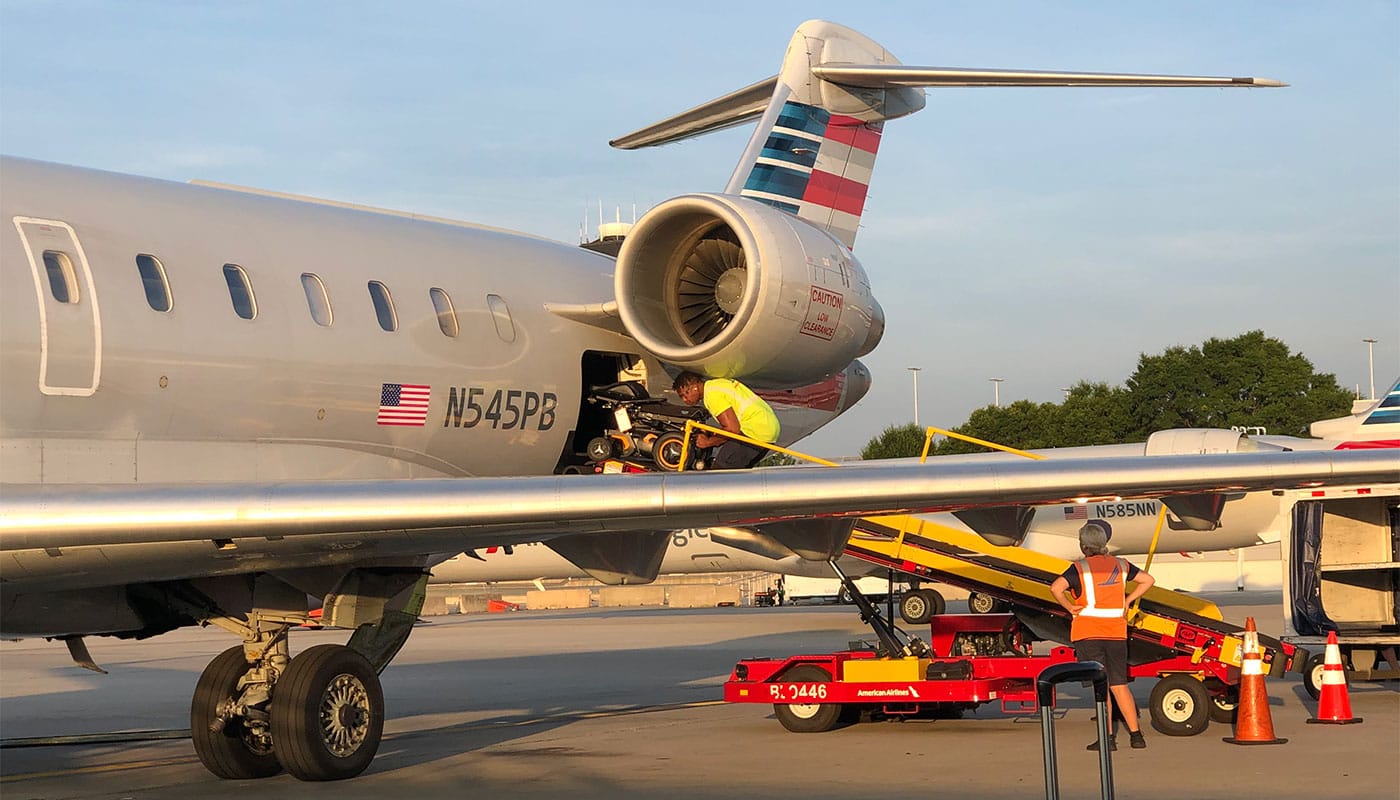 Wheelchair being loaded into cargo hold of American Airlines airplane.