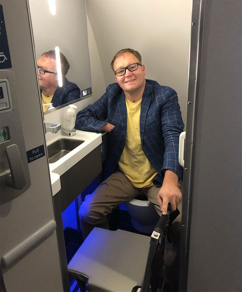 Wheelchair user seated in A220 lavatory.