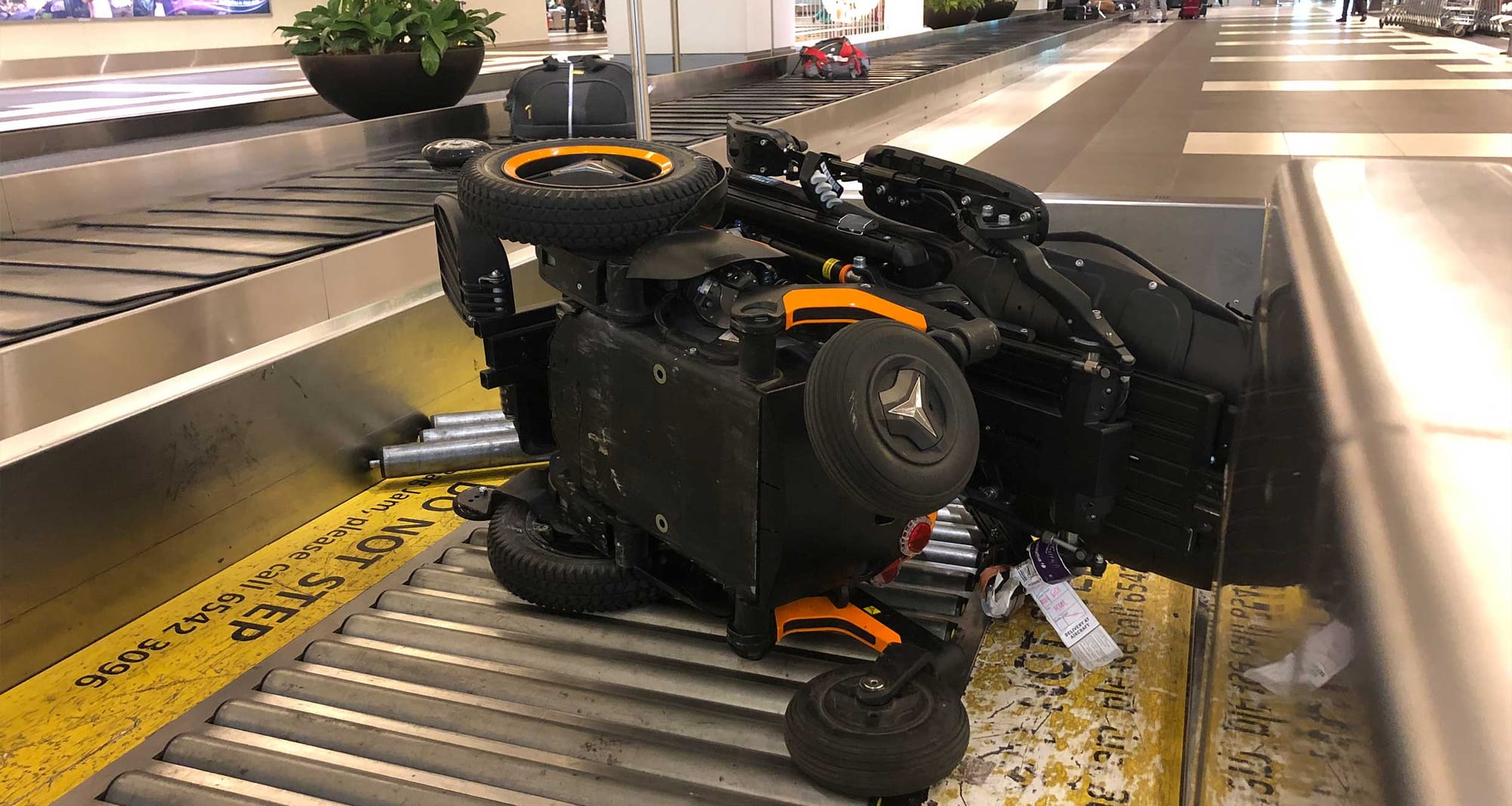 Damaged wheelchair at airport baggage claim.