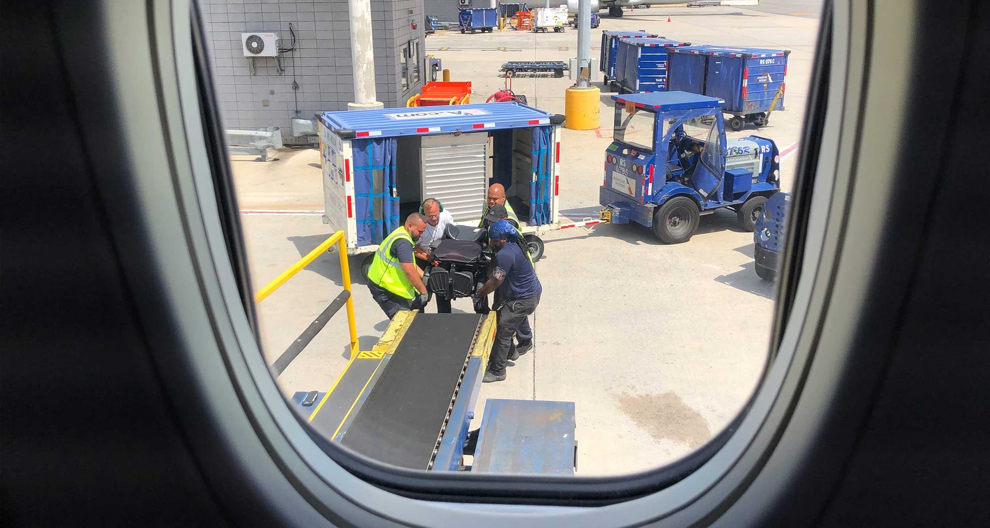 Airline staff loading wheelchair on airplane.