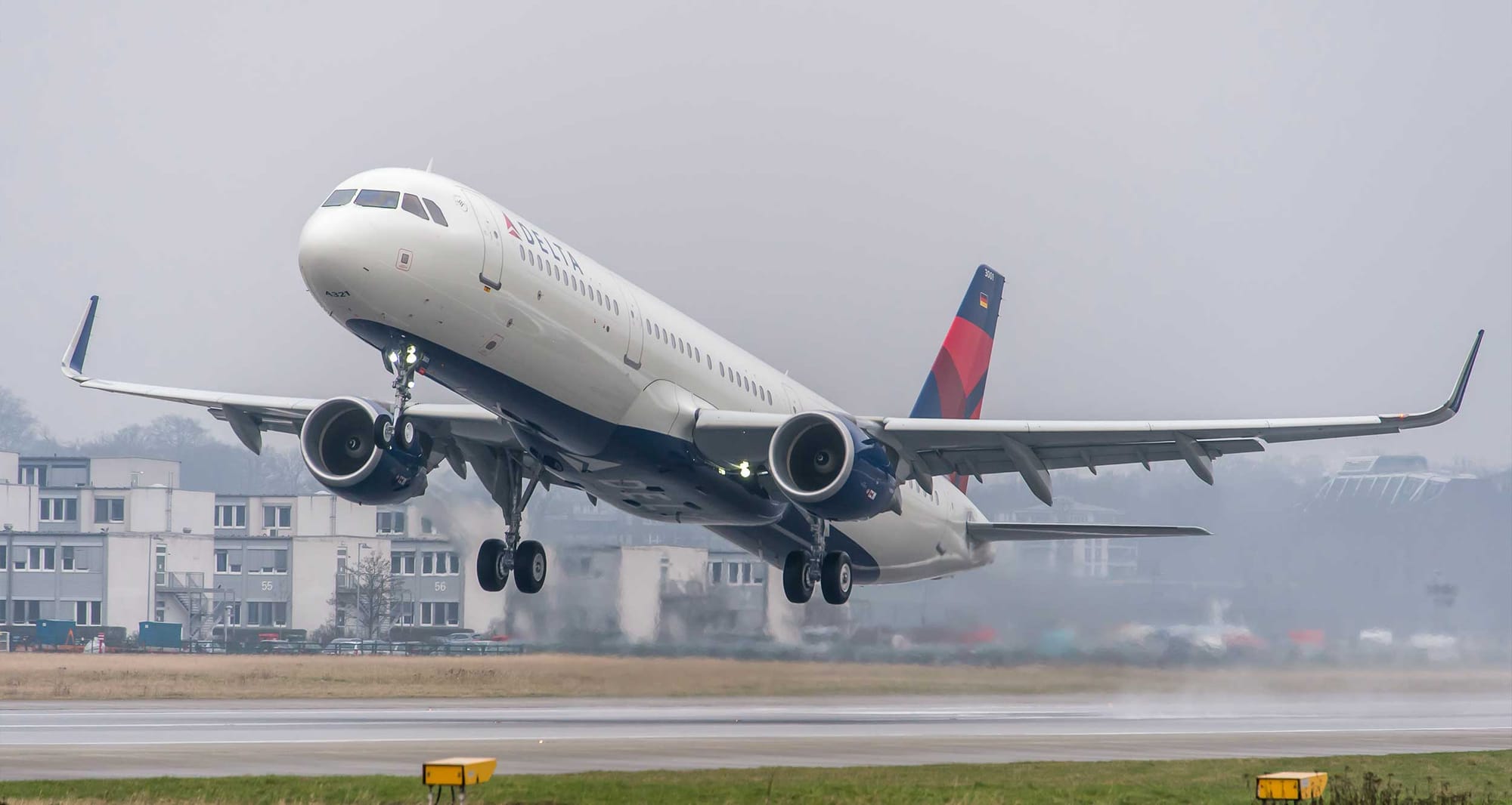 Delta Air Lines Airbus A321 taking off from foggy runway.