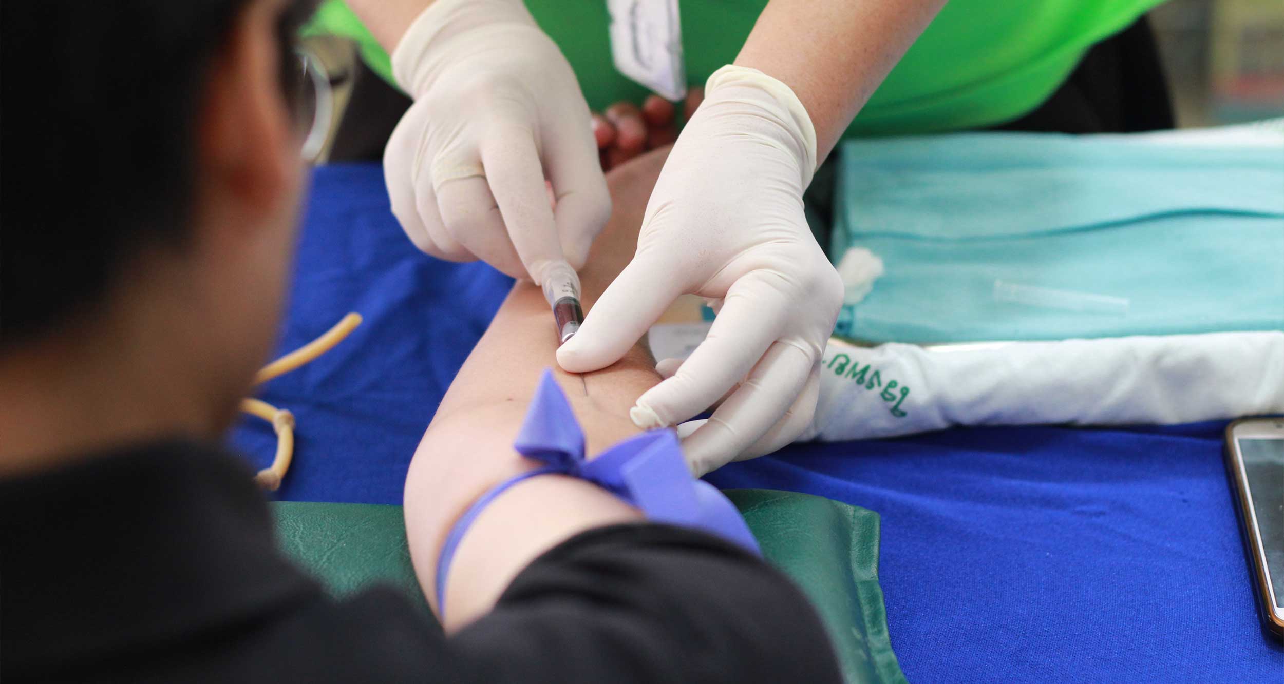 Nurse drawing blood from a man's arm.