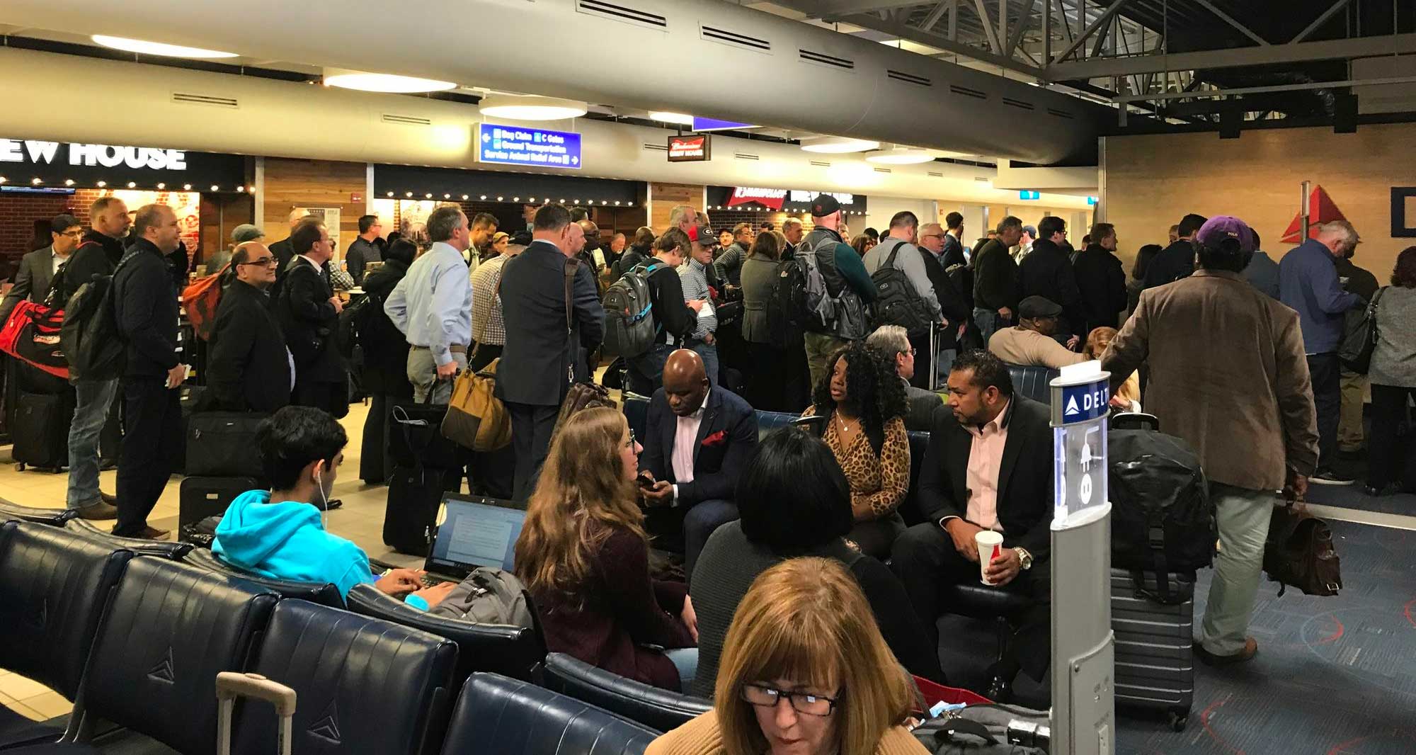 Large group of people congregating in an airport boarding gate prior to the start of boarding.